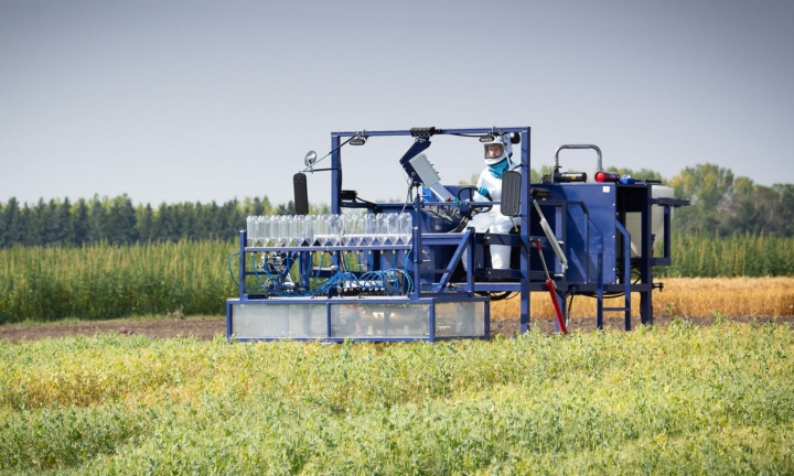 A worker driving a machine over a small crop