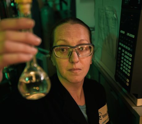 An InnoTech worker holding up a long test beaker with liquid inside