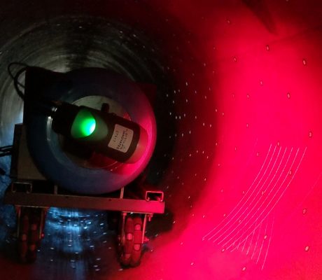 The inside of a large pipe with a laser crawler inspecting the inside.