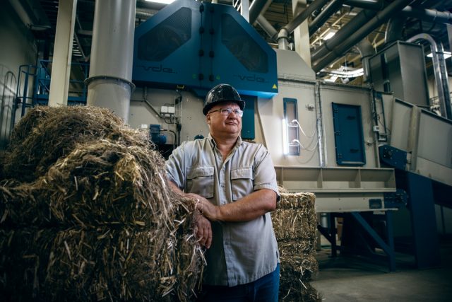 Bio-industrial worker posing beside a hay stack