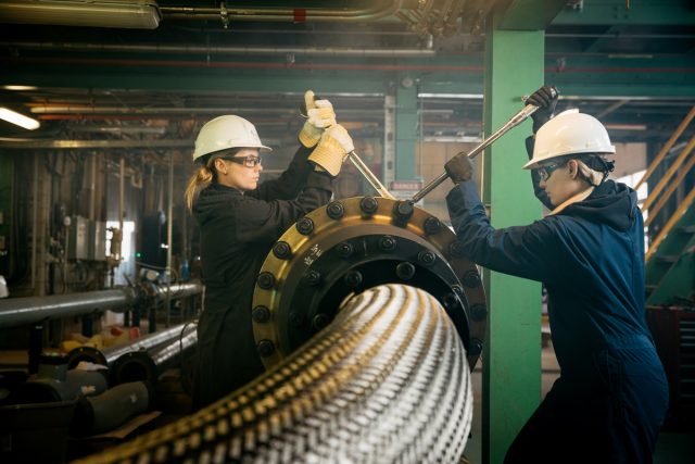 A couple female engineers tightening the bolts on a pipe